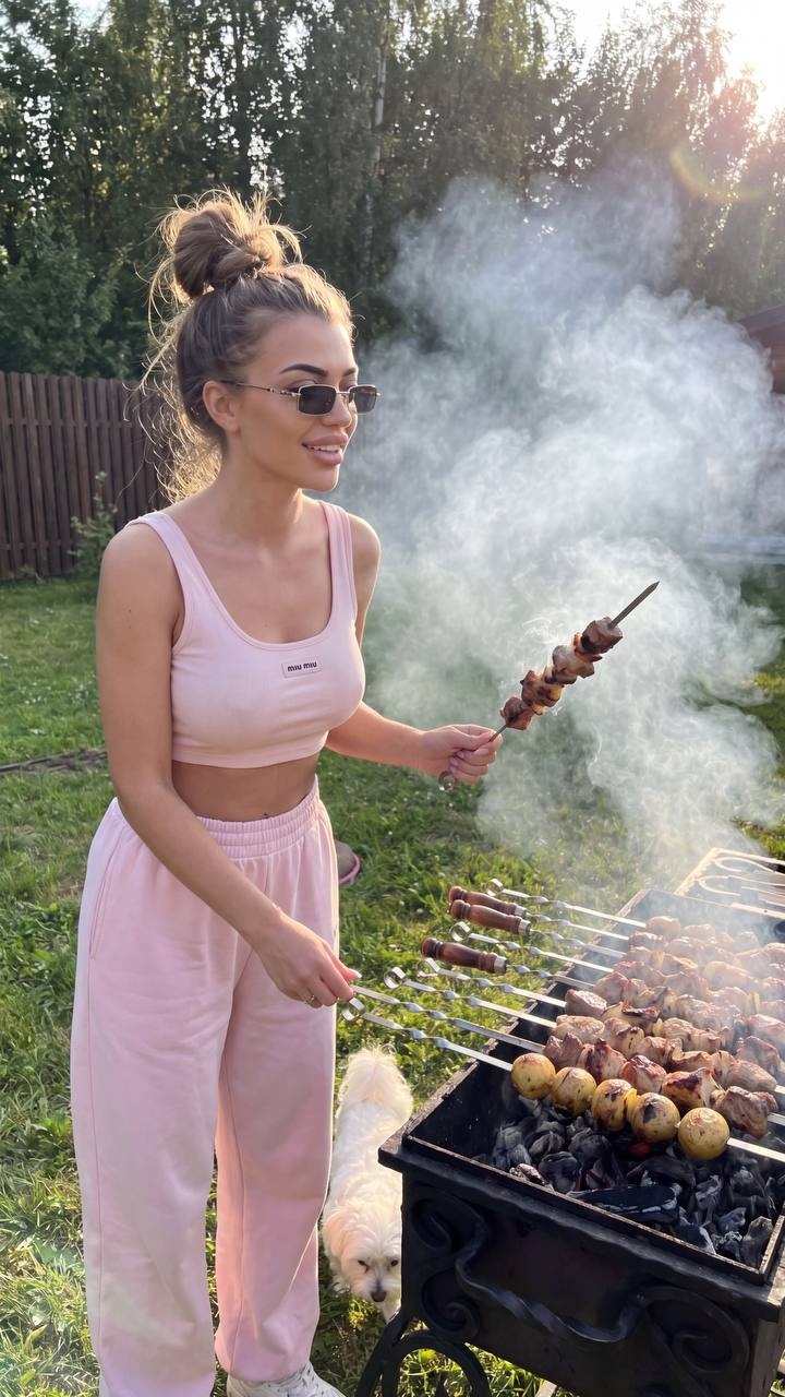 Стильная женщина готовит мясо на барбекю во дворе