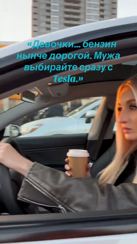 Девушка за рулём белой Tesla в вечернем городе
