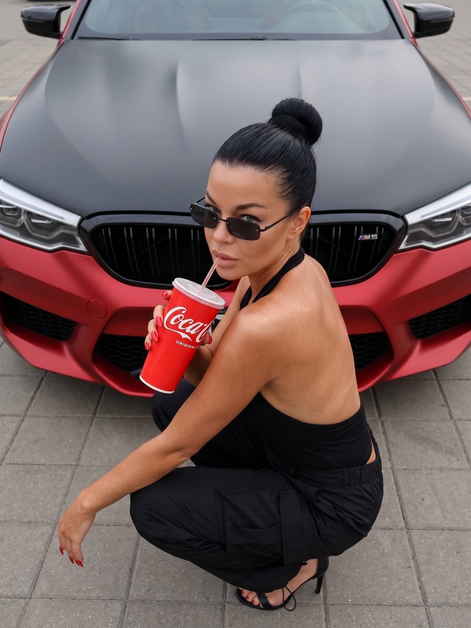Девушка перед красным BMW M5 на тротуаре