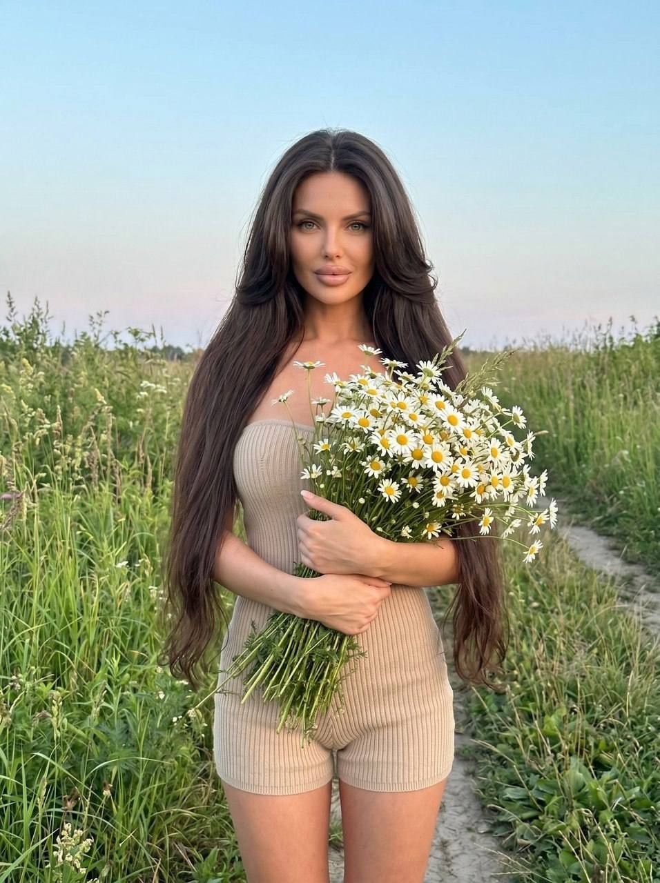 Женщина с букетом ромашек в летнем поле